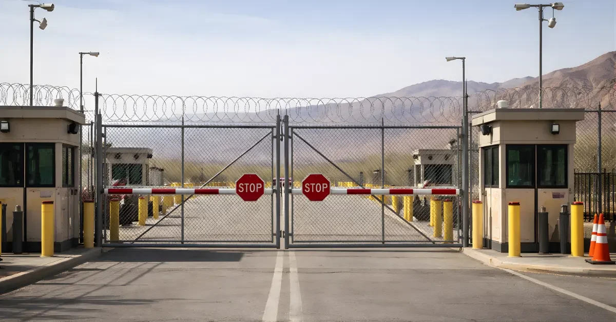 A wide news-style image of a closed border crossing gate with security fencing and checkpoint structures in daylight.