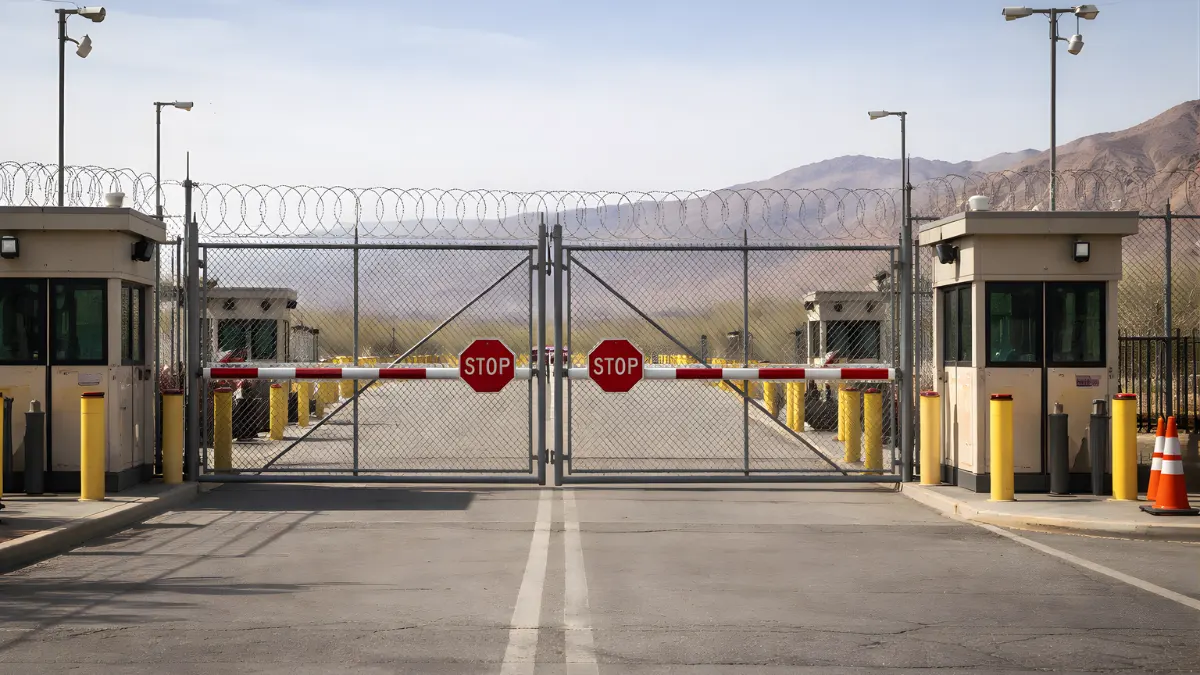 A wide news-style image of a closed border crossing gate with security fencing and checkpoint structures in daylight.