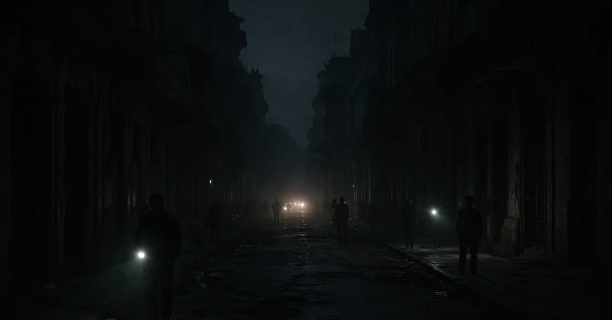 A dark street in Havana, Cuba, entirely without power during a nationwide electrical grid collapse, illuminated only by faint flashlights and headlights.